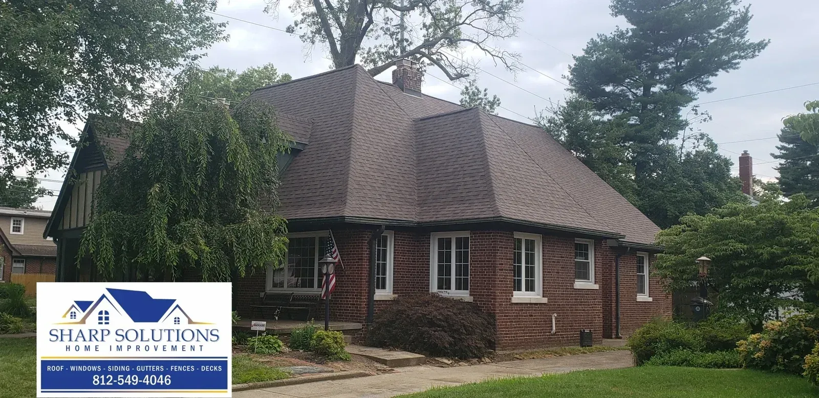 Brick house with a steep shingled roof and a “Staff Solutions” sign in the yard