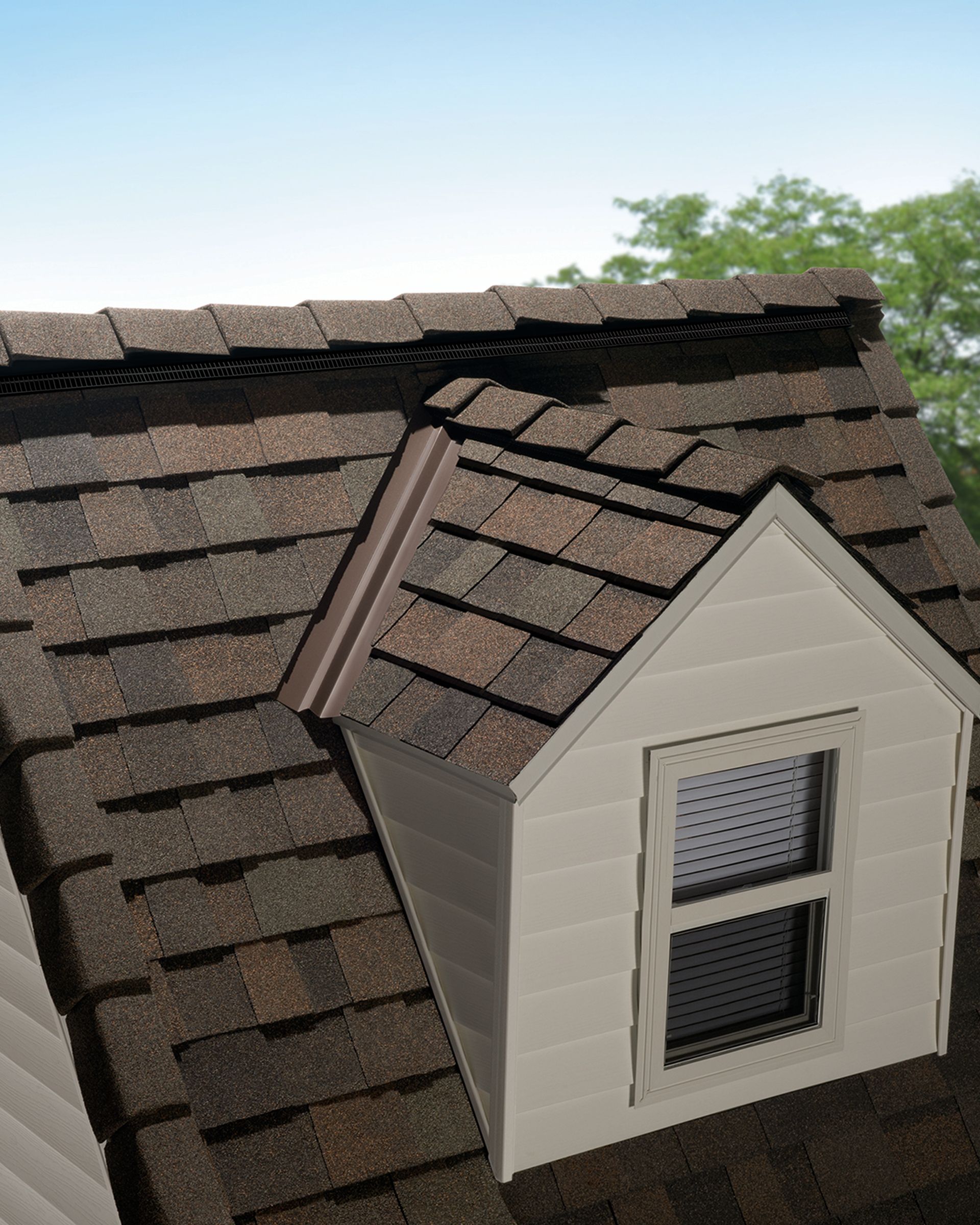 Dormer window with white siding on a shingled roof under a blue sky