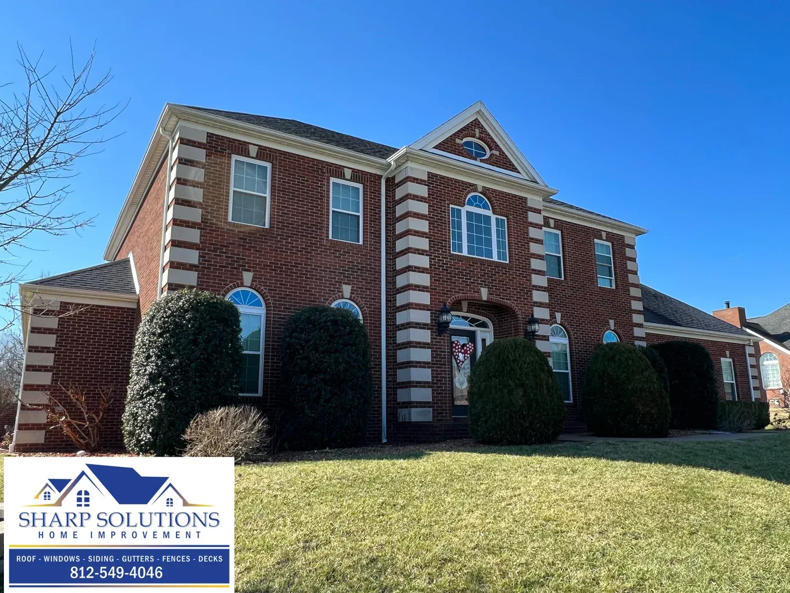 Brick office building with white trim, manicured bushes, and a blue sky above Sharp Solutions signage.