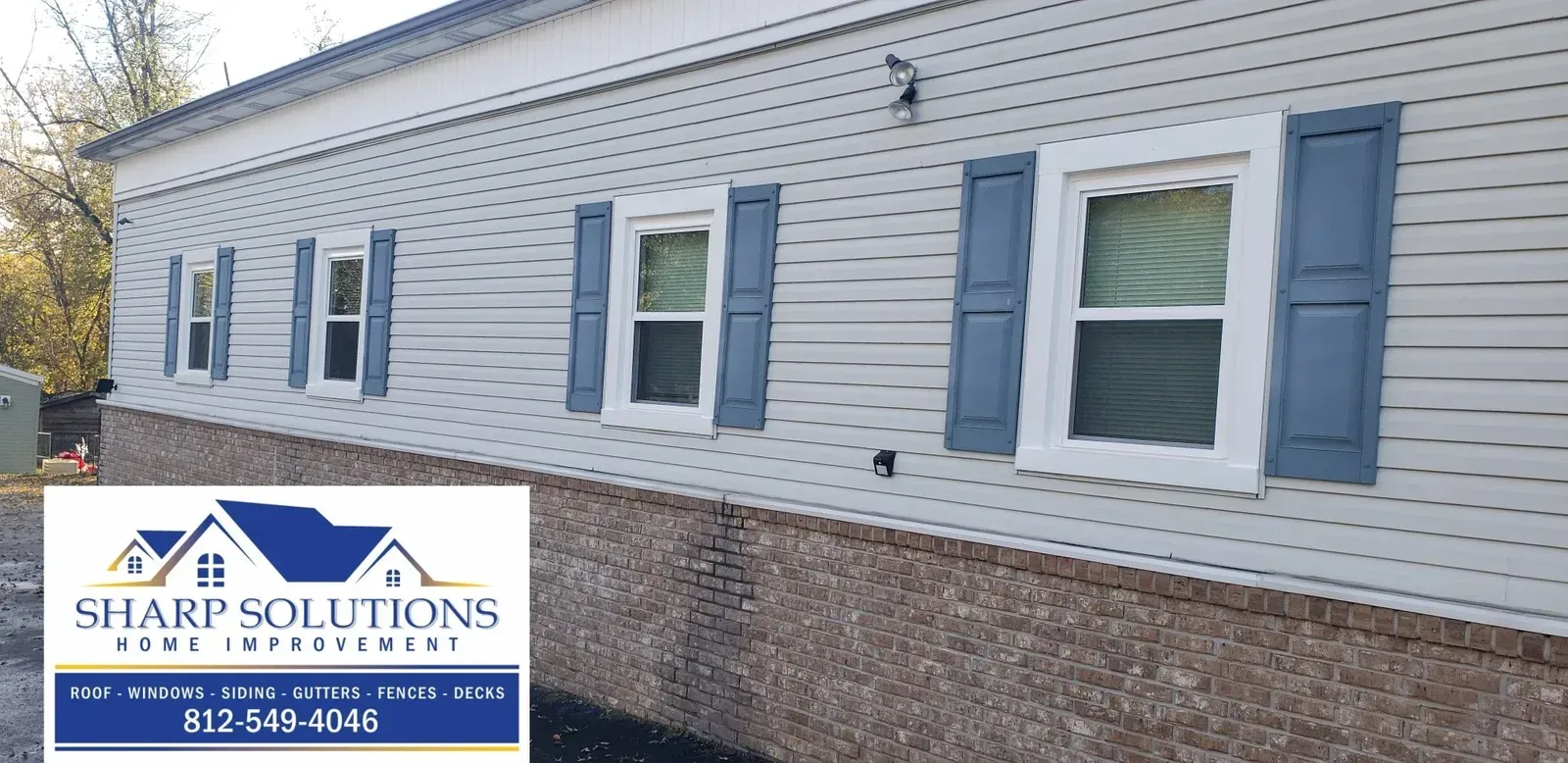 White house exterior with blue shutters and a Sharp Solutions roof repair logo in the corner