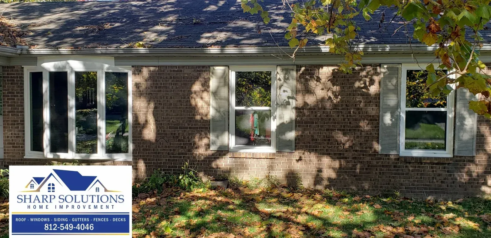 Brick house exterior with white-trim windows and a real estate sign in the front yard