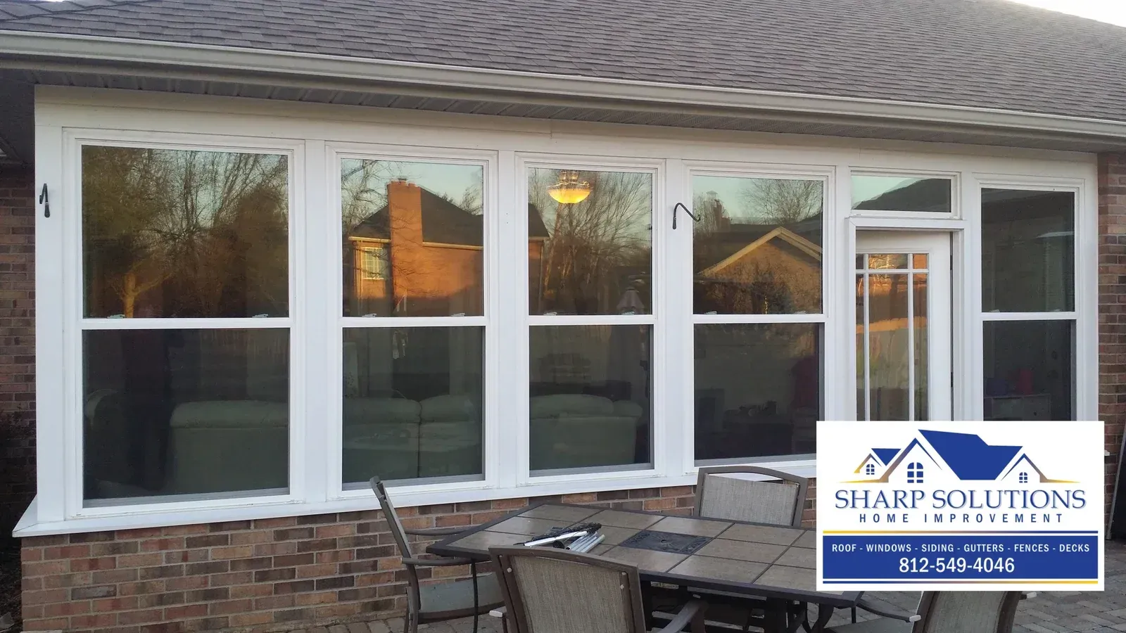 White-trimmed windows on a brick house exterior with a patio and Sharp Solutions logo in the lower right.