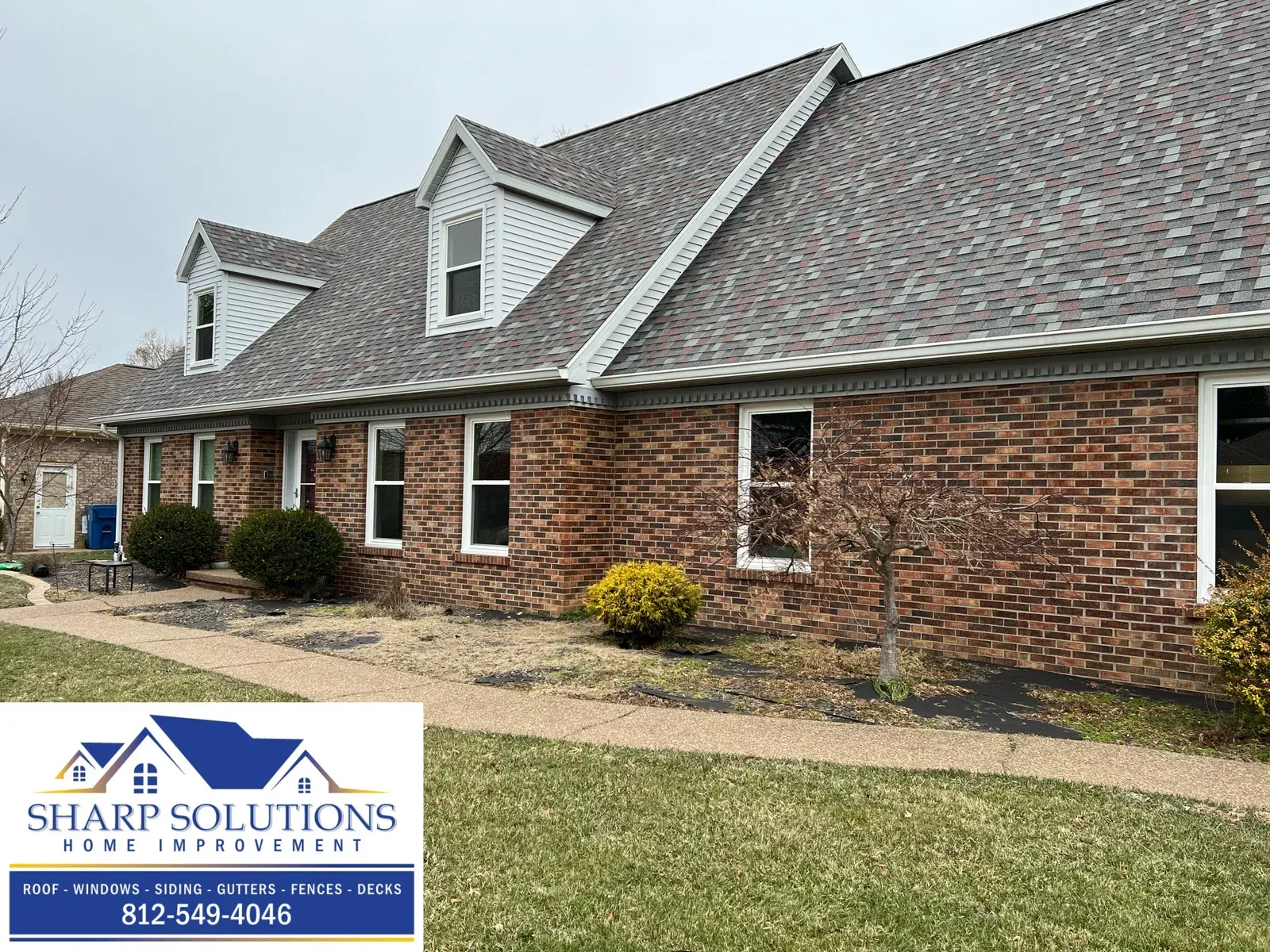 Brick house exterior with gray roof and a Sharp Solutions sign in the lower left corner