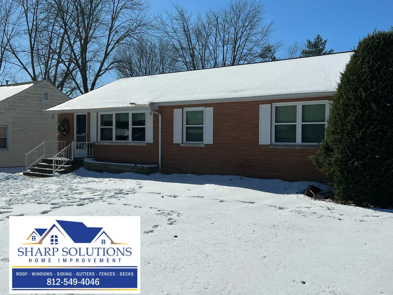 Snow-covered single-story brick house with white-trimmed windows and a Sharp Solutions logo in the lower left.