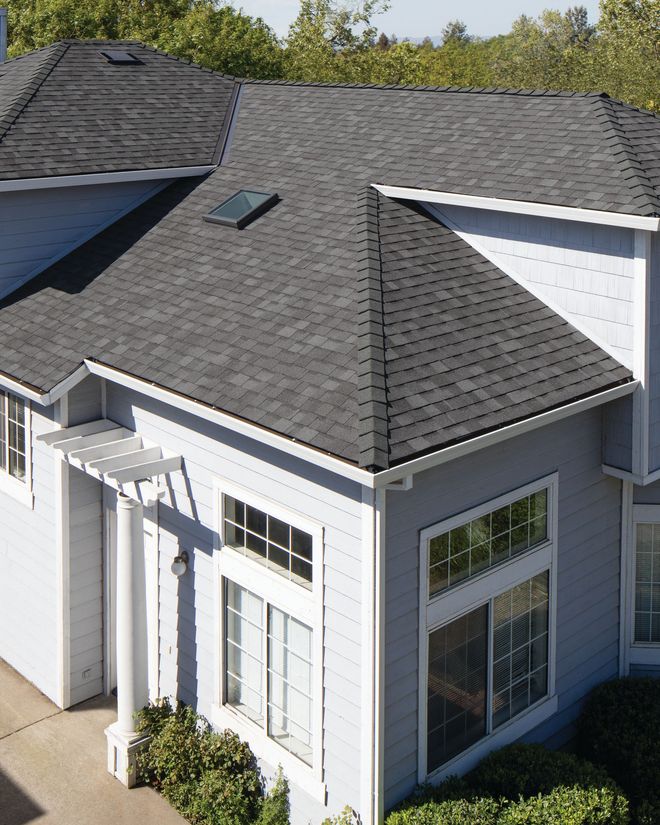 White house exterior with gray shingle roof, large windows, and a small covered entryway