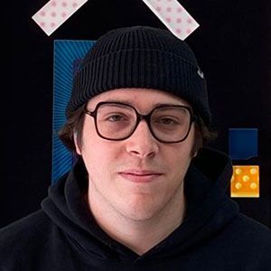 A young man wearing glasses and a beanie is standing in front of a painting.