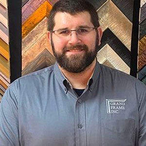 A man with a beard and glasses is wearing a blue shirt.