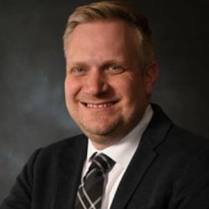 A man in a suit and tie is smiling for the camera.