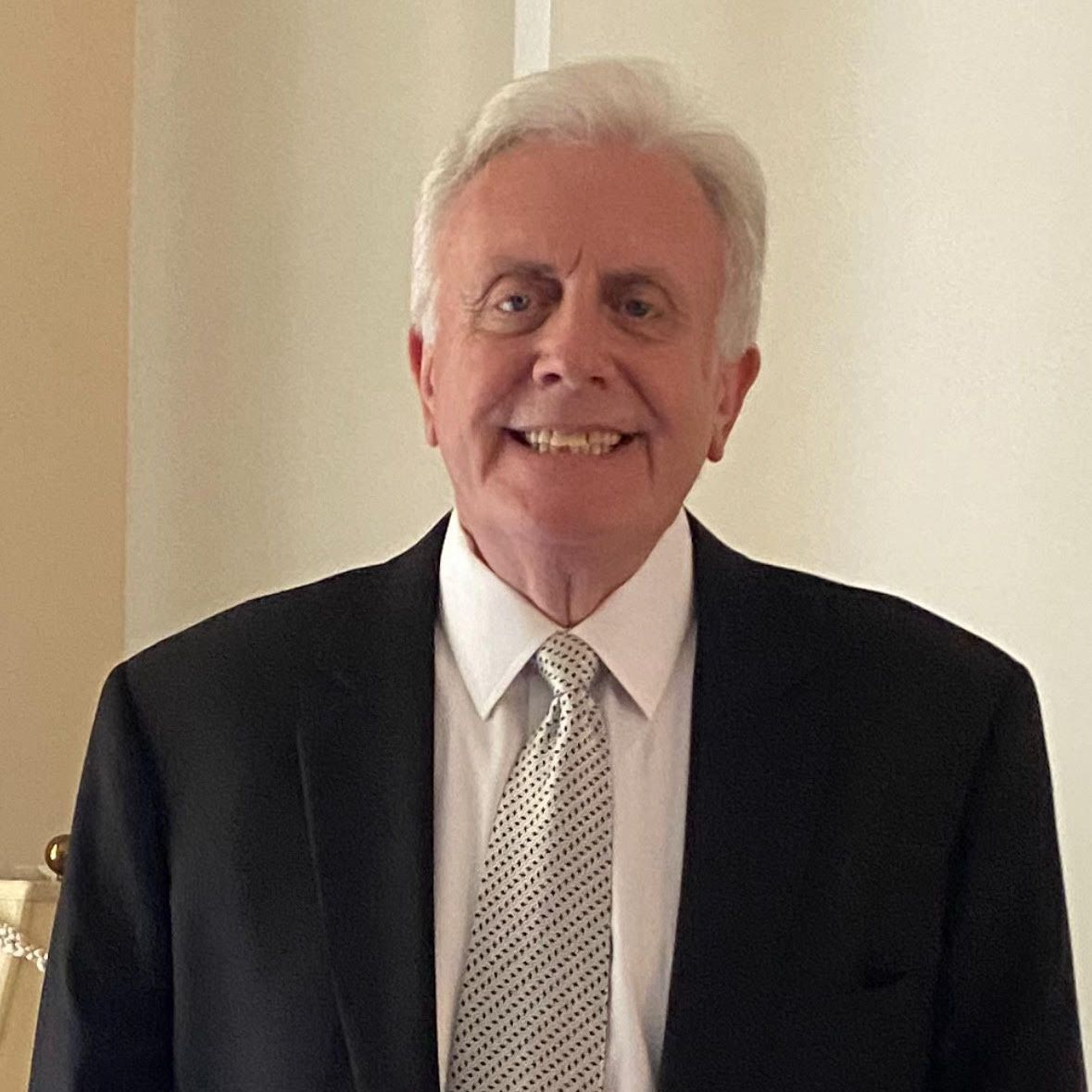 A man in a suit and plaid shirt is smiling for the camera.