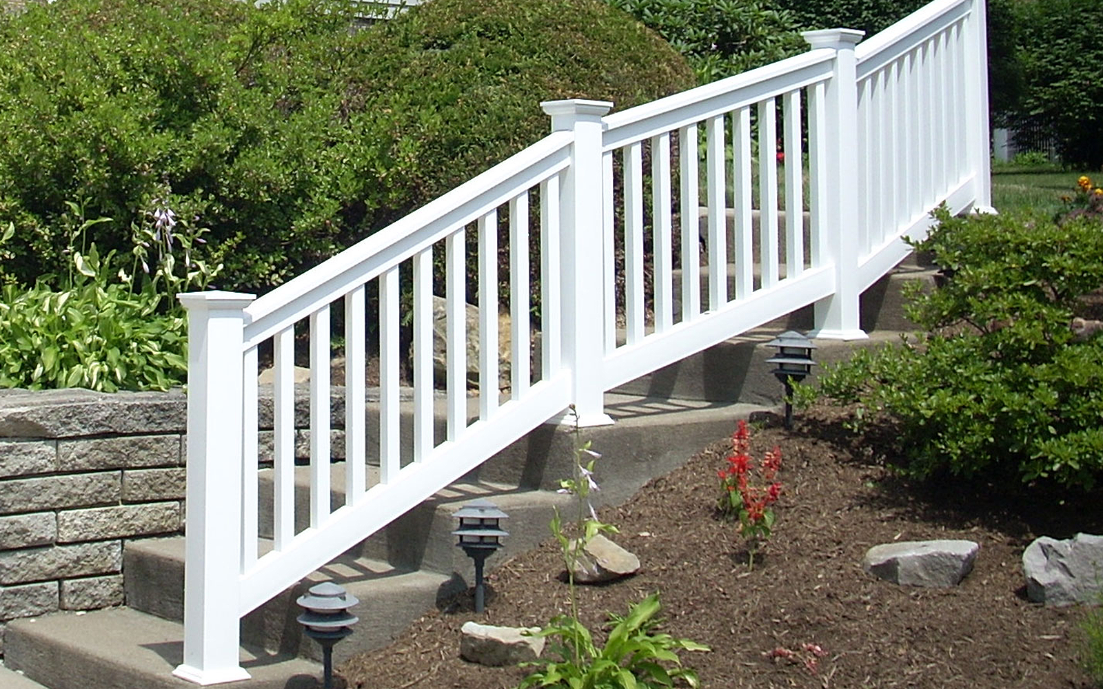 A white fence surrounds a set of stairs in a garden