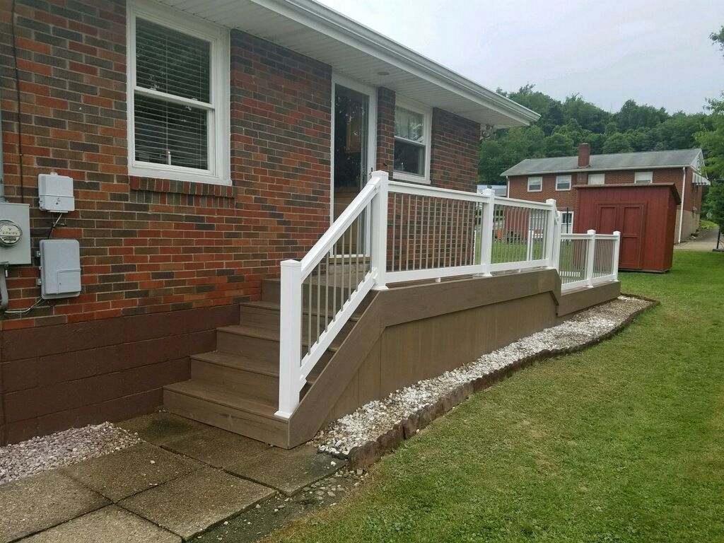 A brick house with a deck and stairs in front of it.