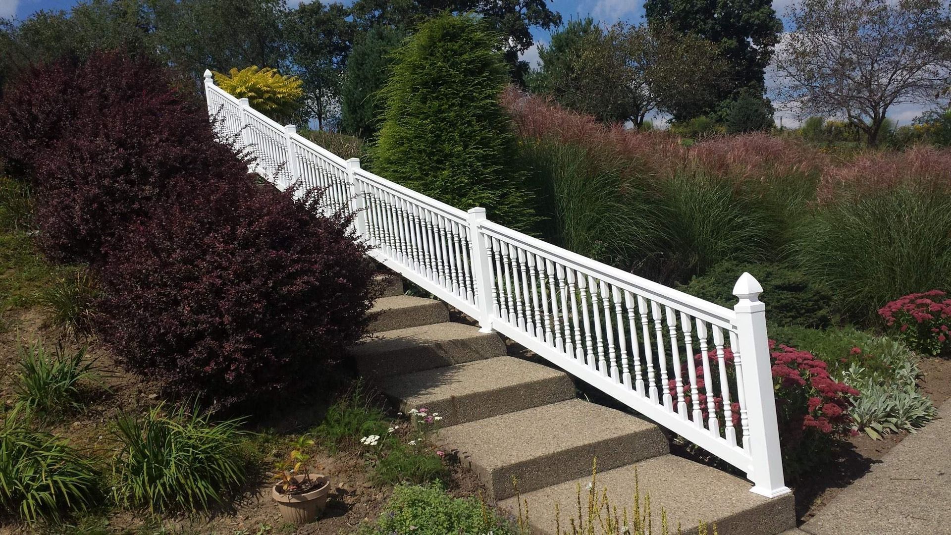A white fence surrounds a set of stairs in a garden.