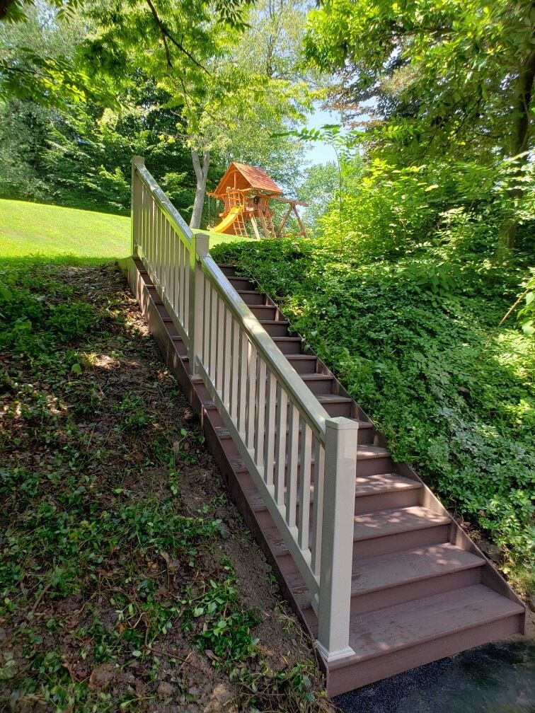 A set of stairs leading up to a deck with a swing set in the background.