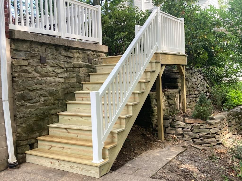 A wooden deck with stairs leading up to it and a white railing.