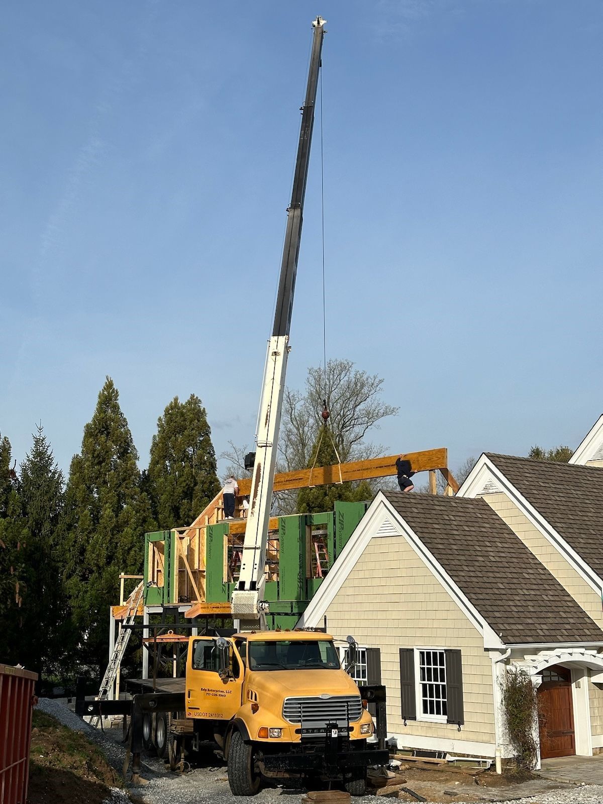 A yellow truck is parked in front of a house under construction.