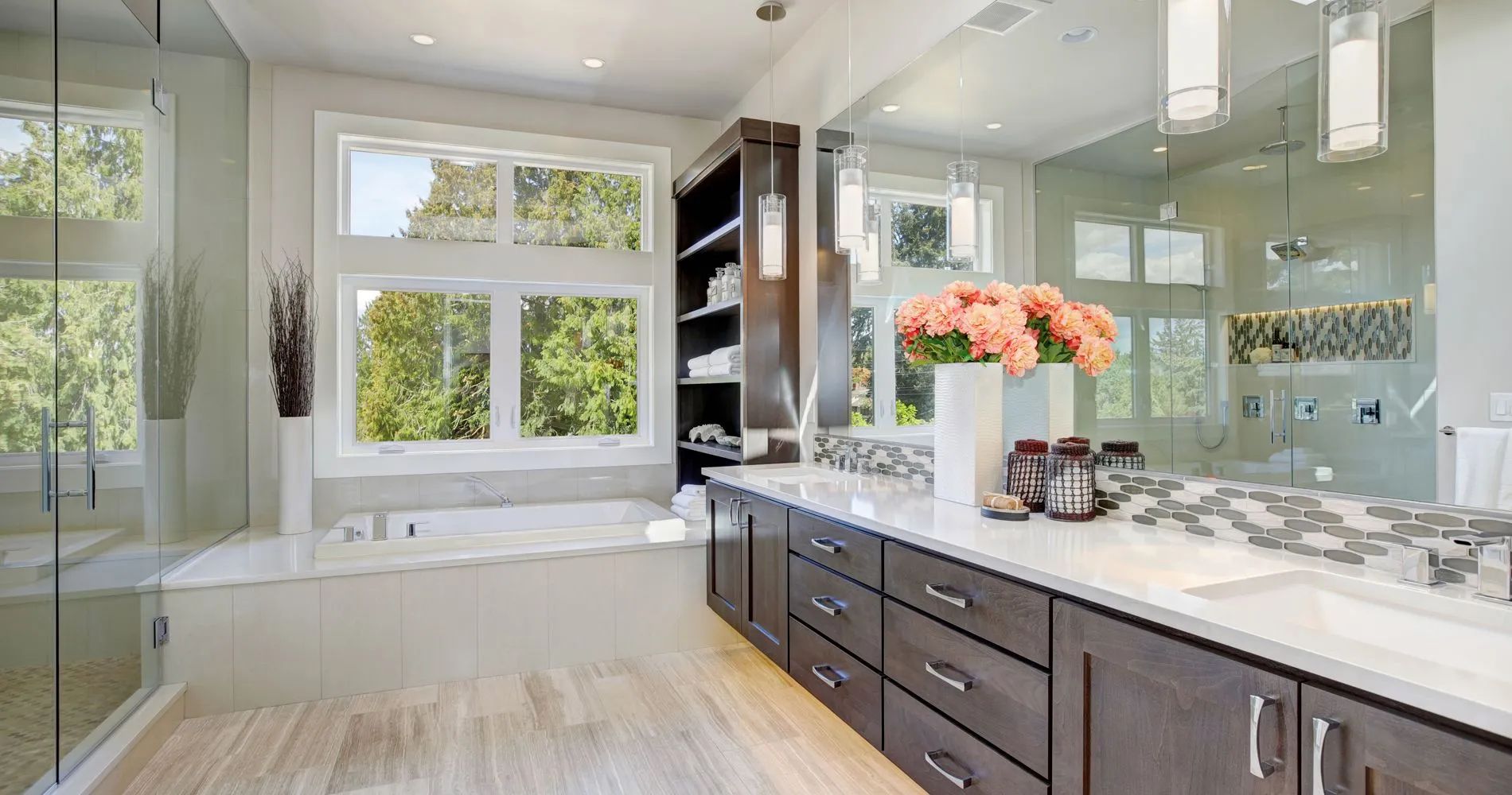 Bright modern bathroom with double vanity, white marble counters, large mirror, and window seating area