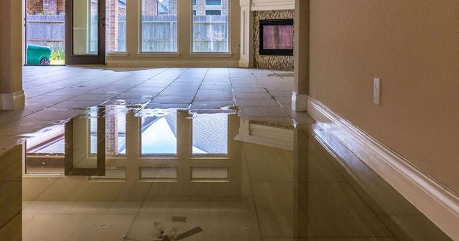 Flooded hallway with standing water reflecting windows and doorway in a vacant house