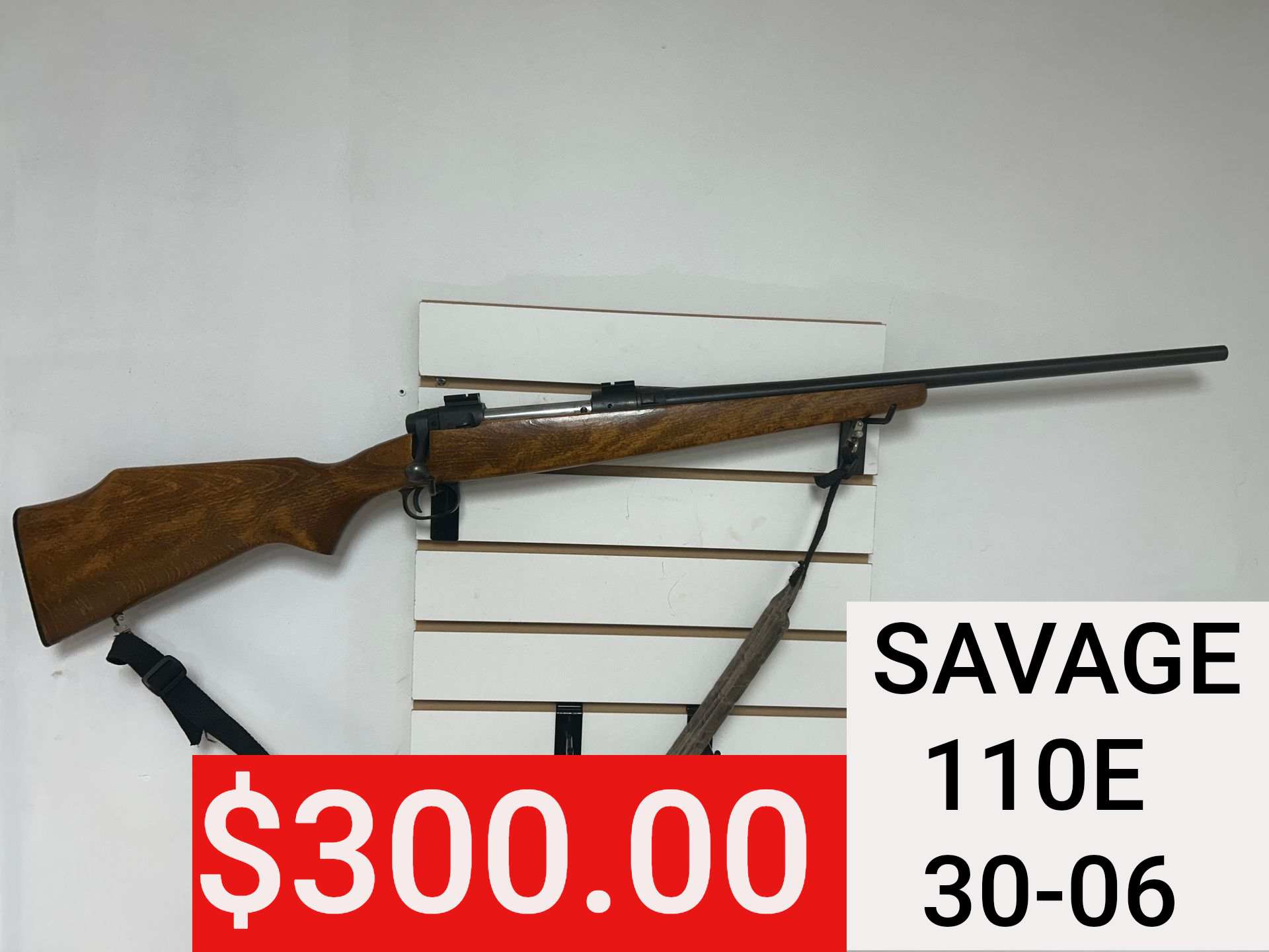 Savage 110E .30-06 rifle with $300 price tag displayed on wall