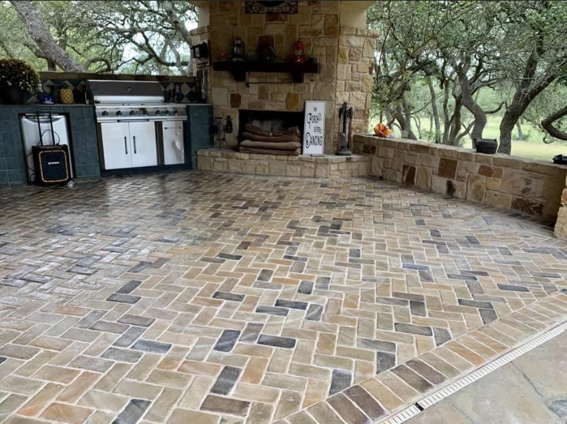 A brick patio with a fireplace and a grill.