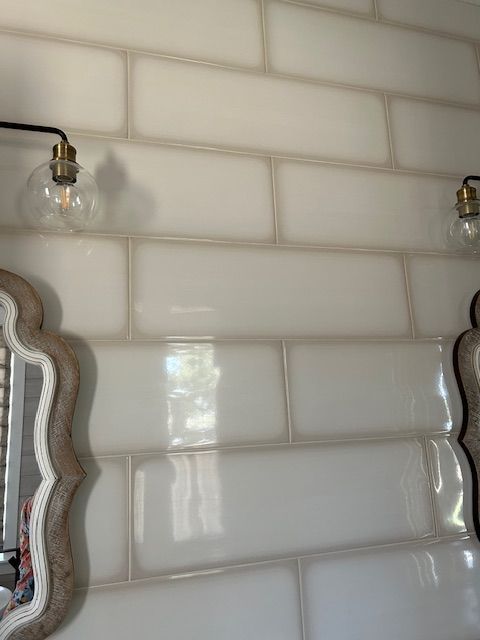 A bathroom with white tiles and a mirror.