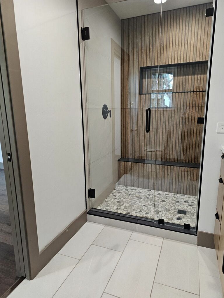 A bathroom with a walk in shower with a glass door.
