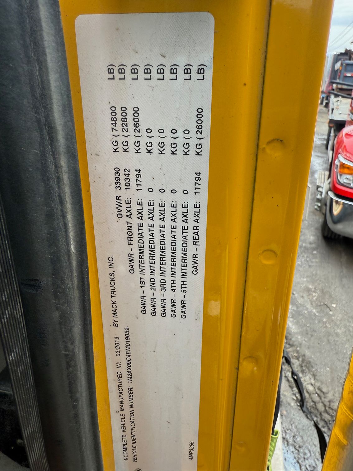 A close-up of a white truck weight capacity label with black text on a yellow door frame.