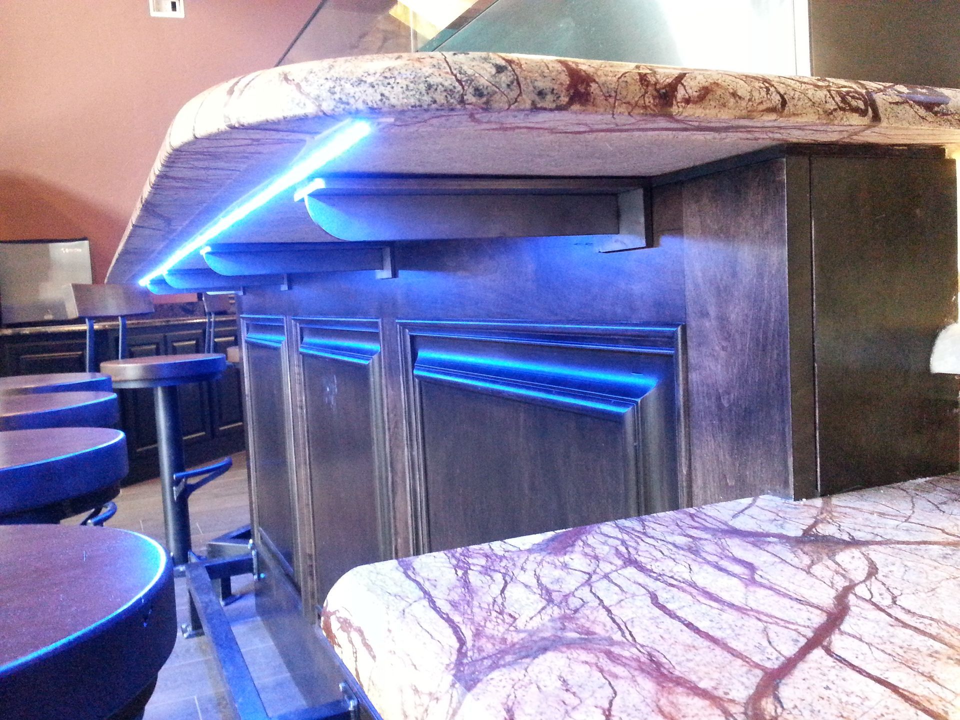 Bar with blue LED lighting, granite countertops, and bar stools.
