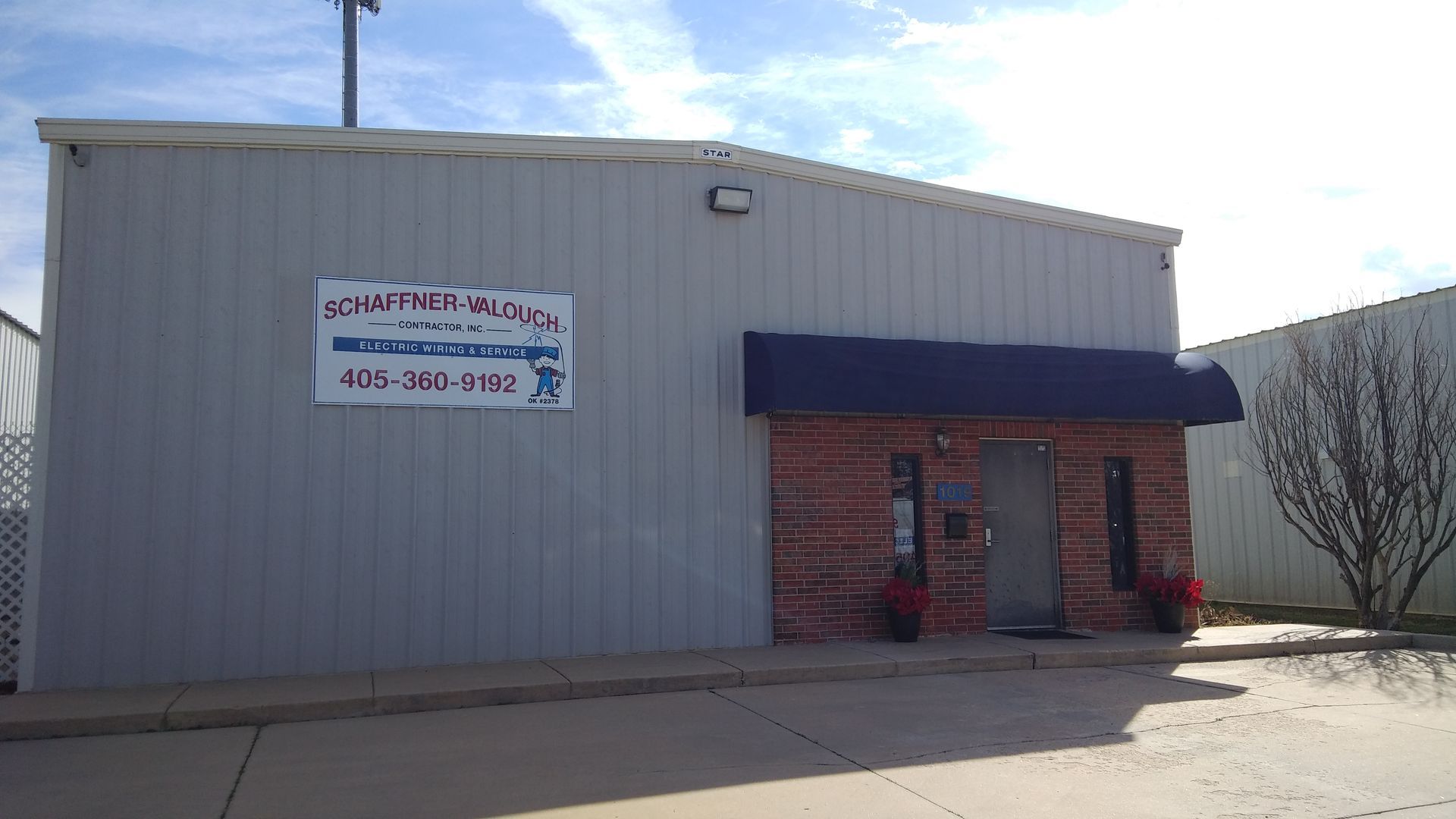 A building with a brick facade and a blue awning. Sign reads 