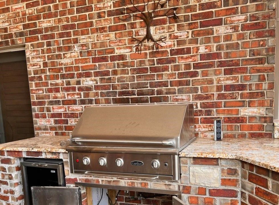 Outdoor brick kitchen with stainless steel grill and countertop.