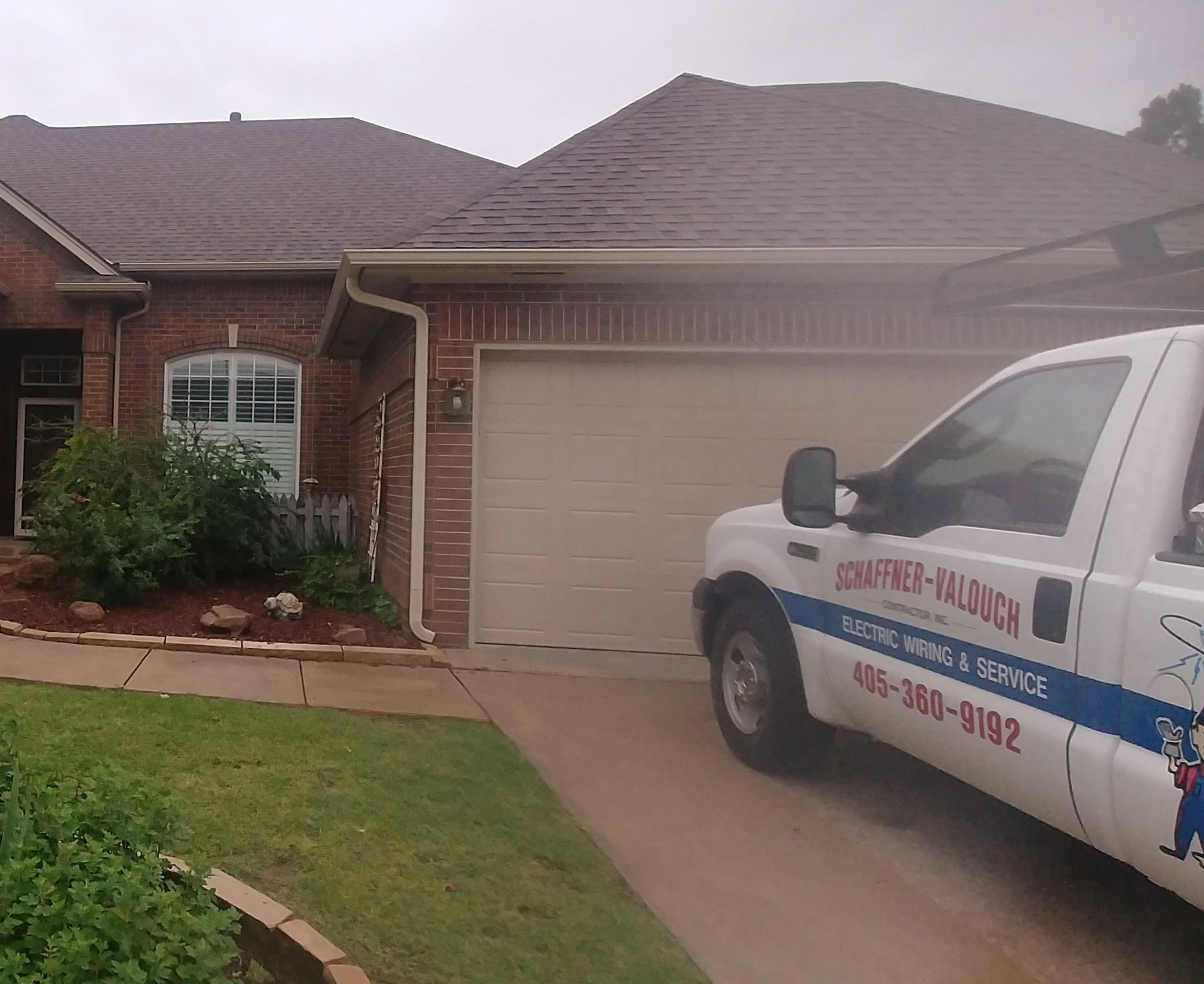 Truck parked in front of a brick house with a garage door. The truck has the words 