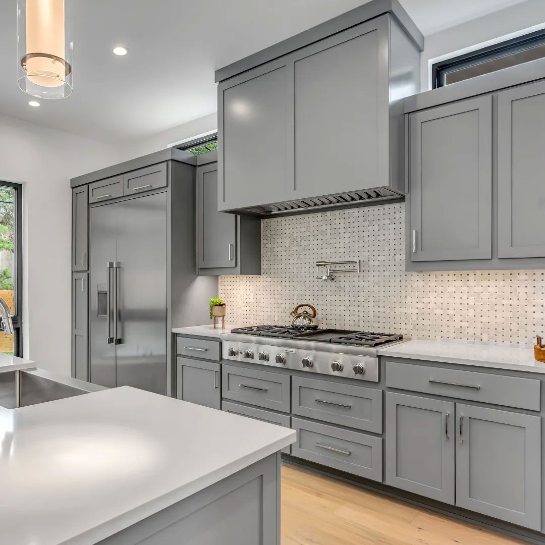 Modern gray kitchen with stainless steel appliances, white countertops, and light wood flooring.