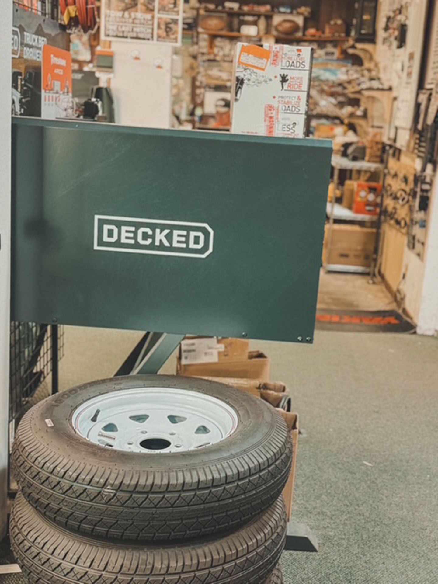 Green DECKED display stand with stacked tires outside a shop entrance