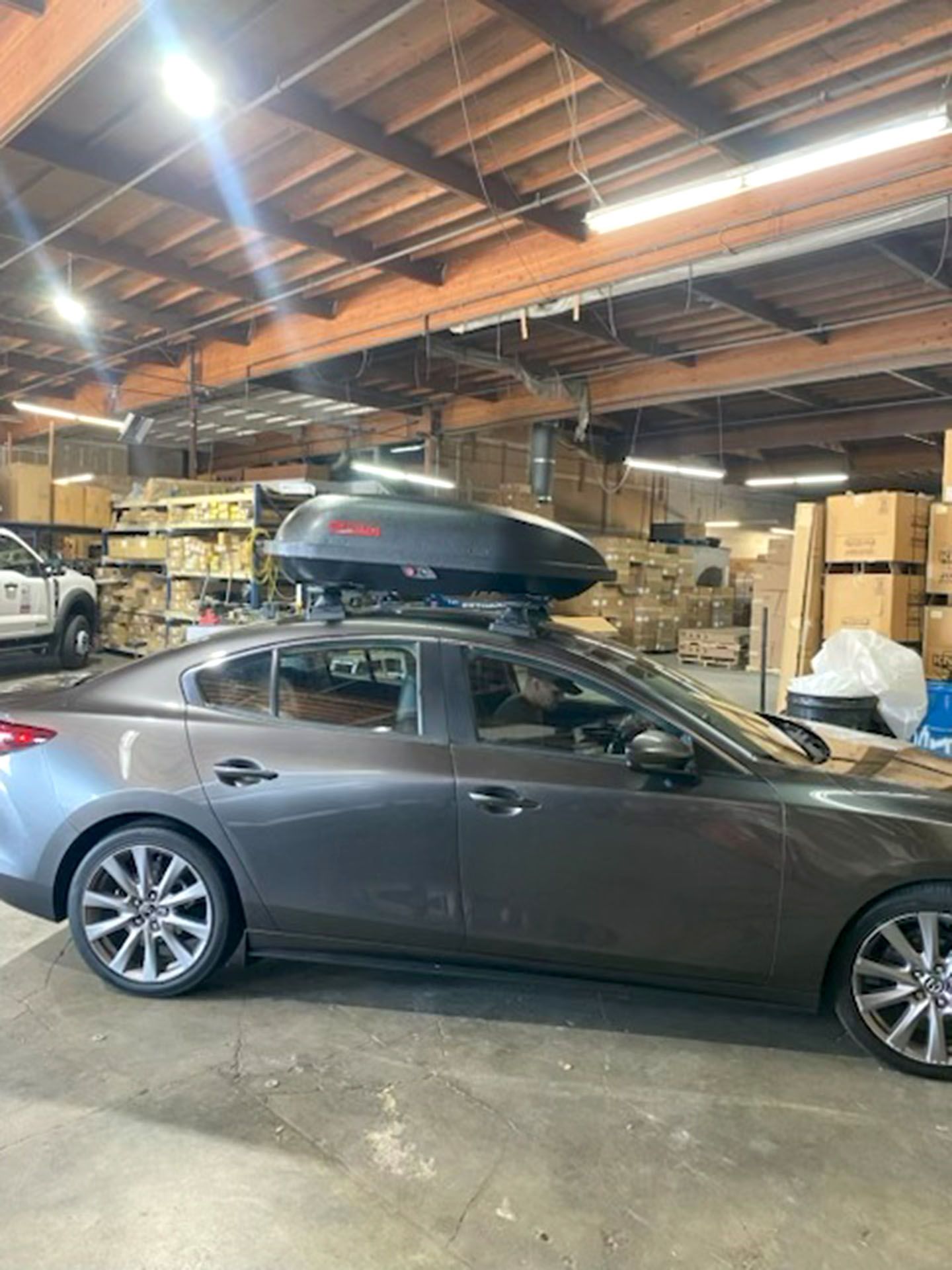 Gray sedan with a roof cargo box parked inside a shop