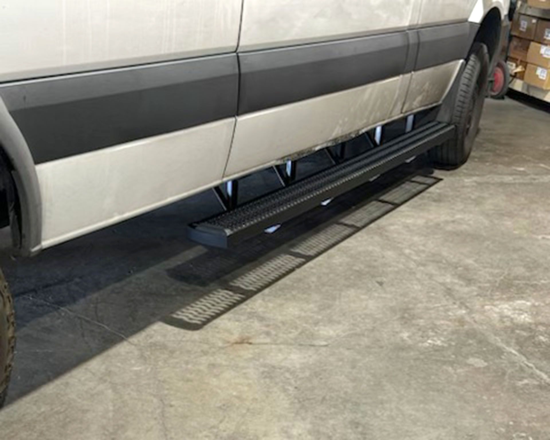Side view of a silver van with a black running board in a garage