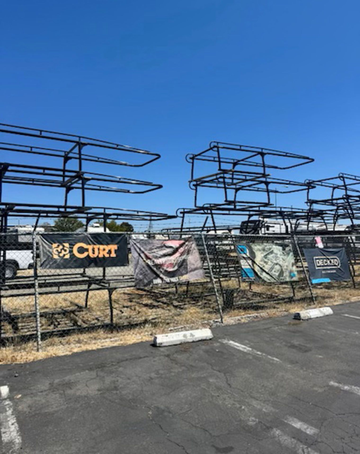 Outdoor lot with empty black metal racks and banners under a clear blue sky