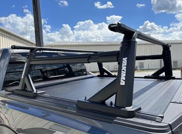Black Yakima roof rack mounted on a truck bed under a bright blue sky