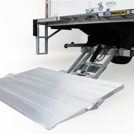 Large metallic loading ramp attached to a truck lift gate, extended downward against a white background.