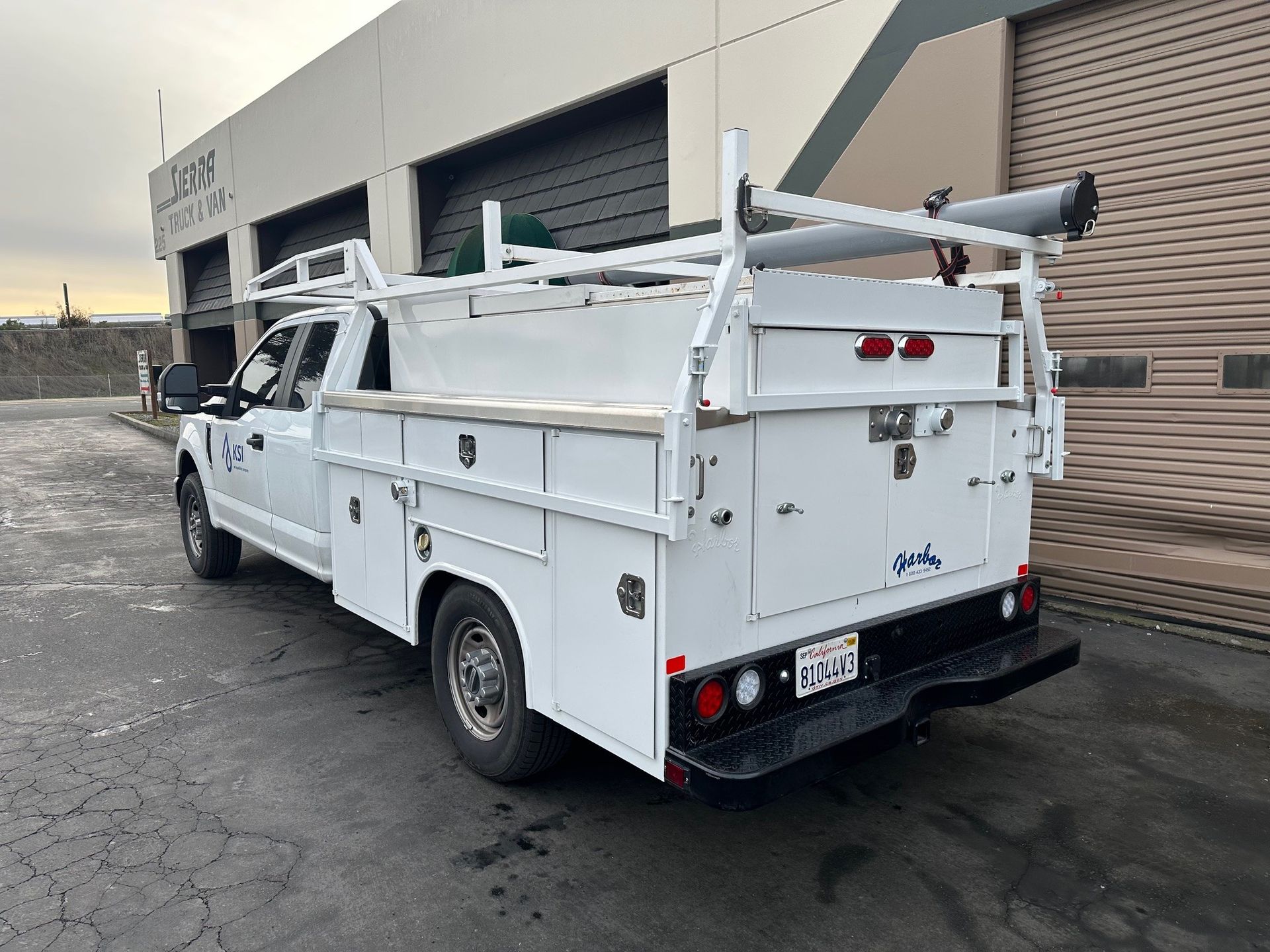 A white utility truck is parked in front of a building.