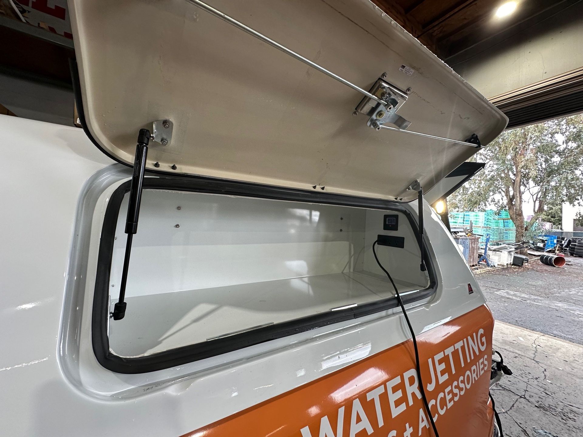 A white and orange van with the trunk open.