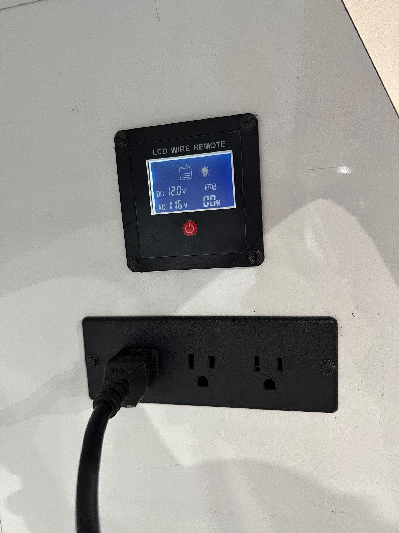 A black plug is plugged into a black electrical outlet