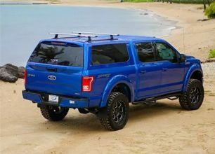Blue SUV parked on a sandy beach near the water