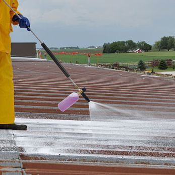 a person is spraying a roof with a sprayer 