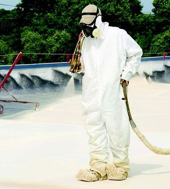 a man in a white suit is spraying a roof with a hose 