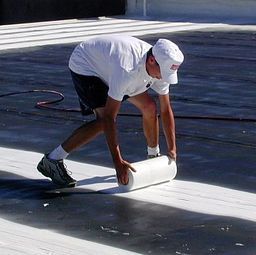 a man is rolling a roll of white tape on a concrete surface 