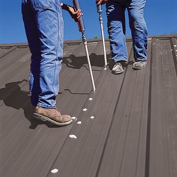 two men are standing on top of a metal roof 