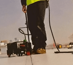 a man is standing on a roof using a machine 