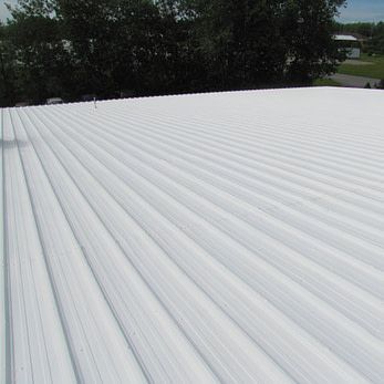 a close up of a white roof with trees in the background 
