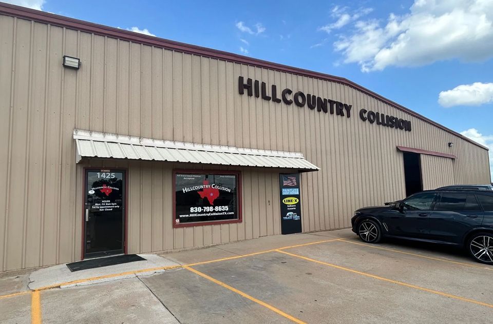 A car is parked in front of a building that says hill country collision.