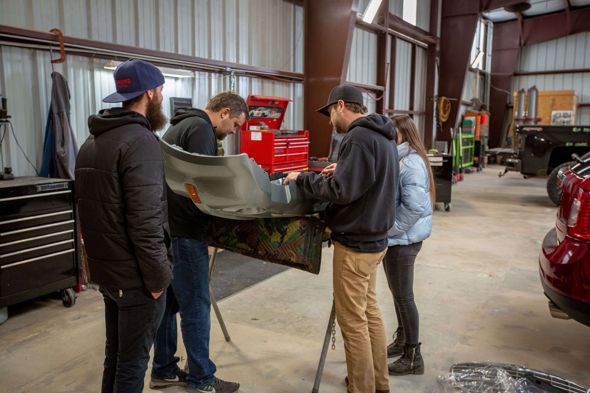 A group of people are working on a car in a garage.