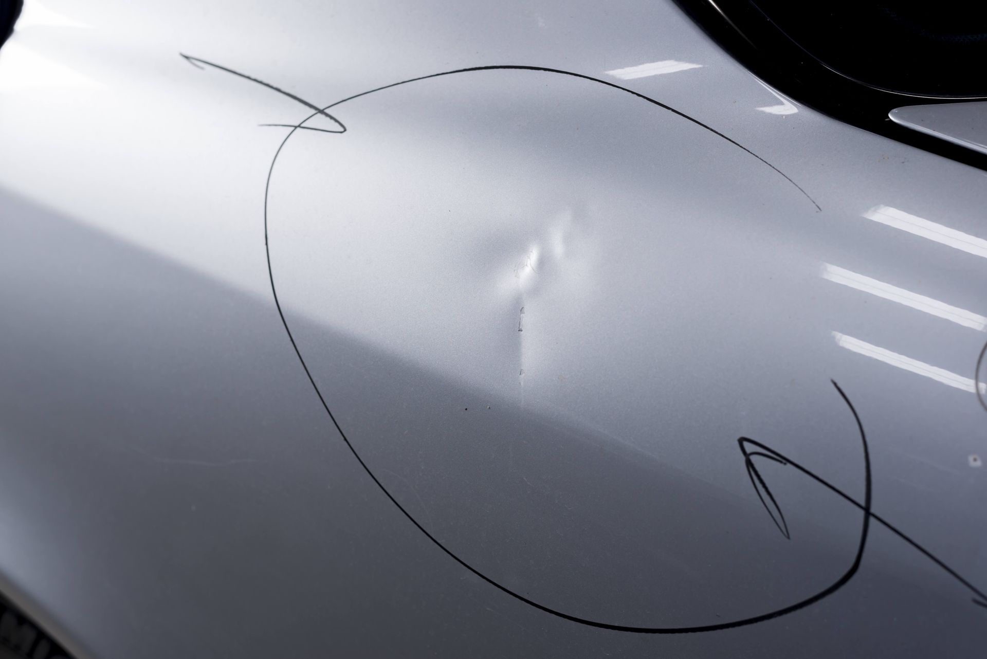 A close up of a car dent with a circle drawn on it